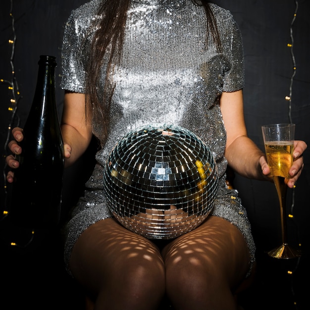 Foto gratuita signora con bottiglia di champagne, vetro e palla da discoteca