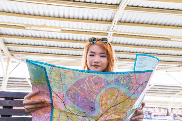 Free photo lady with map on seat on platform