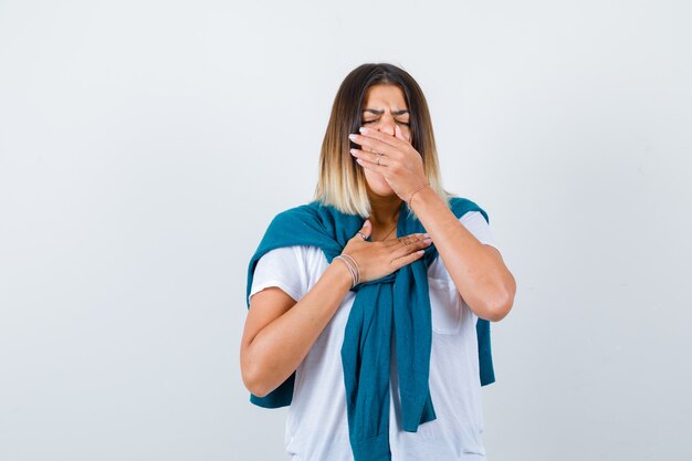 Lady with tied sweater in white t-shirt yawning and looking sleepy , front view.