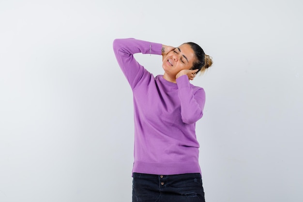 Lady in wool blouse keeping hands on ears and looking delighted 