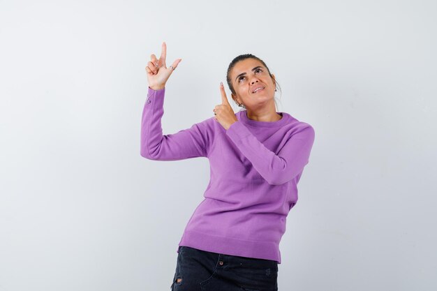 Lady in wool blouse pointing up and looking merry 