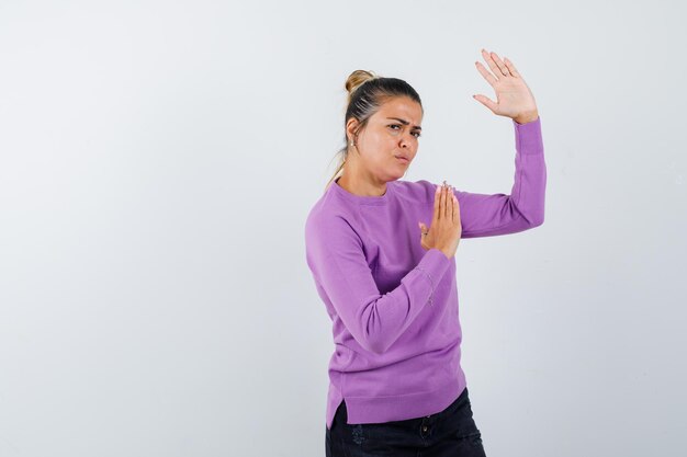 Lady in wool blouse showing karate chop gesture and looking spiteful 