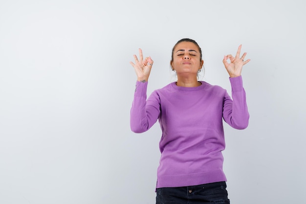 Lady in wool blouse showing meditation gesture and looking relaxed 