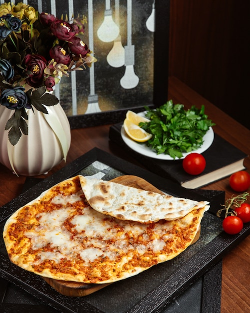 Lahmacun on wooden board with lemon and green