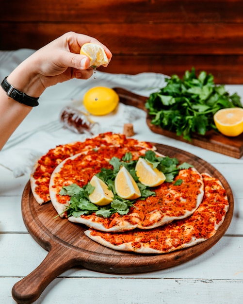 Free photo lahmajun with meat a slice of lemon herbs on a round board _