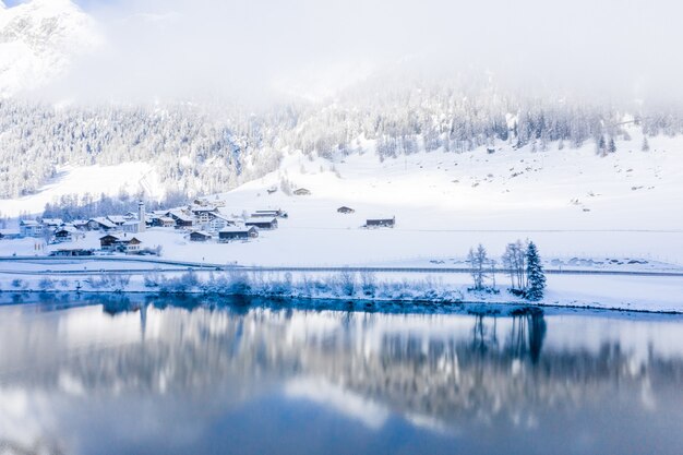 Lake by the snow-covered hills captured on a foggy day