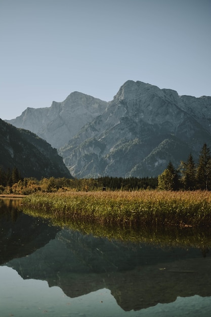 Lake reflecting the mountainous landscape surrounded by dry grass and trees