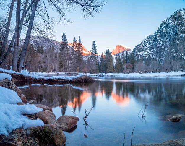 A lake surrounded by rocks, trees and mountains in Yosemite during winter