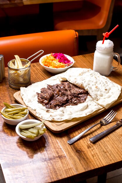 Lamb doner kebab in flatbread served with pickles and fries vertical