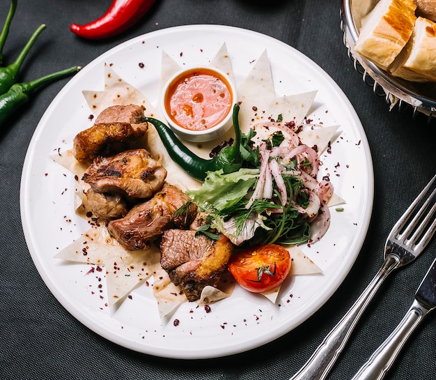 Lamb kebab on lavash onion greens tomato lettuce pepper top view