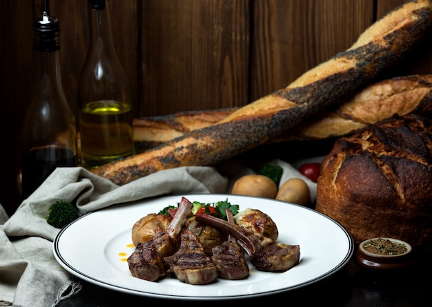 Foto gratuita kebab di costolette di agnello servito con patate grigliate e insalata