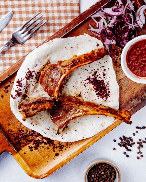  lamb ribs kebab with red onions on a wooden board