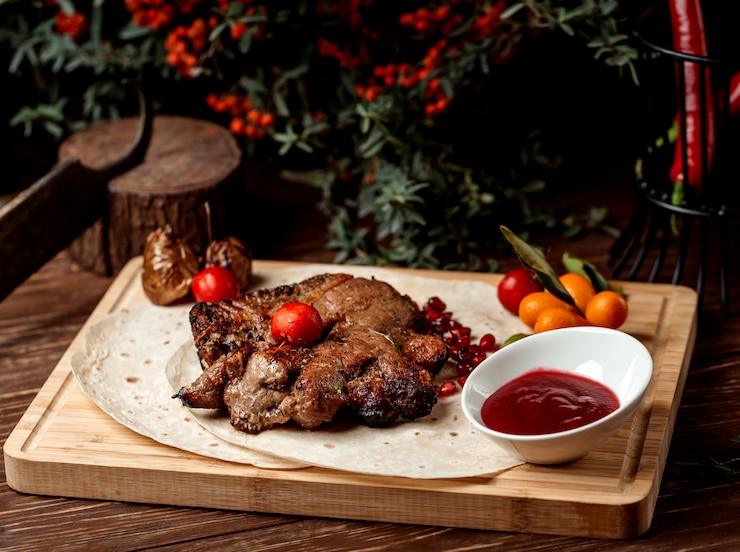 Free Photo lamb steak garnished with pomegranate, sour sauce and tomato