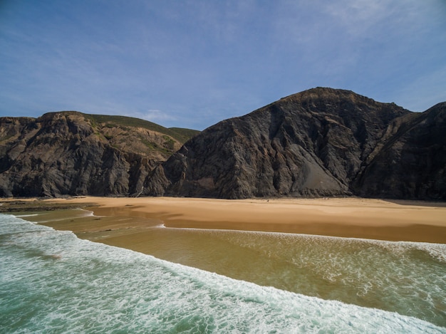 Free photo landscape of a beach surrounded by high rocky mountains under a blue sky in portugal, algarve