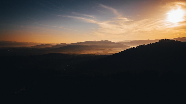 日の出の日光の下で丘のシルエットの風景