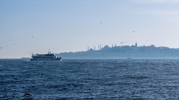 Пейзаж стамбульских зданий вдалеке и плывущая турецкая лодка