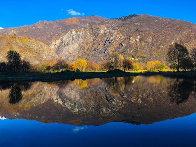 Foto gratuita il paesaggio del lago con il riflesso di colline e alberi su di esso sotto la luce del sole durante il giorno