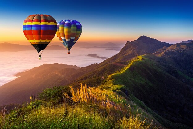 朝の霧と日の出の熱気球と山の風景。