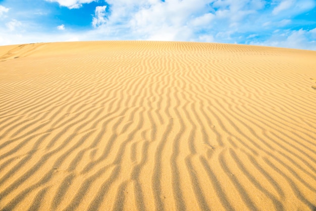 Пейзаж пустынных песчаных дюн и голубого неба с облаками над ними
