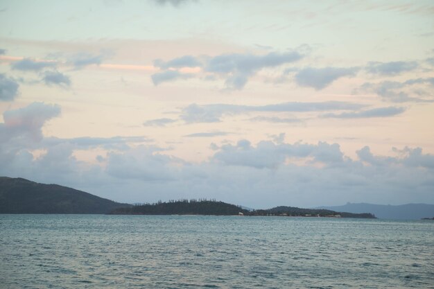 曇り空の下の緑に覆われた丘に囲まれた海の風景