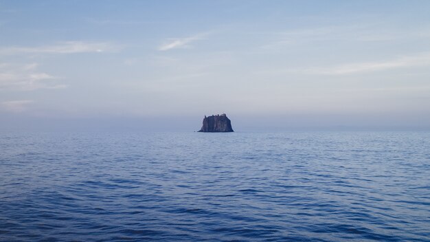 Landscape of the sea with a rock under a cloudy sky during daytime