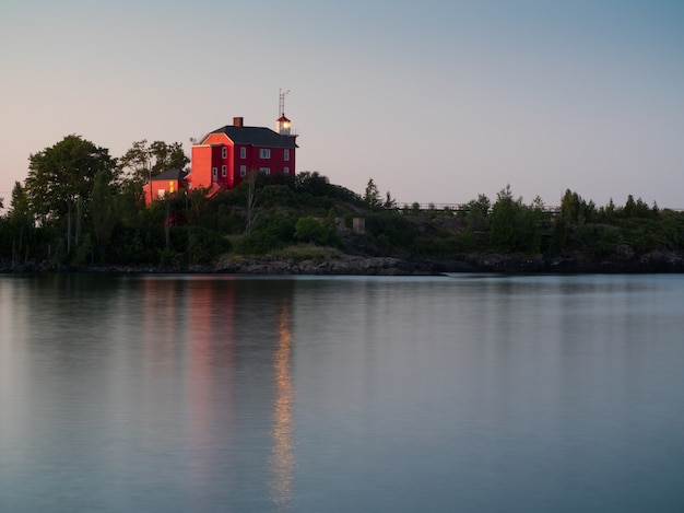 Landscape shot of a calm lake with a red house on the shore