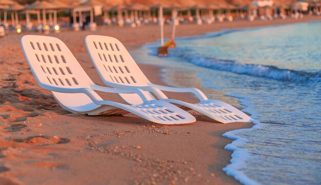 Paesaggio di due sedie a sdraio solitarie vicino al mare e bellissima alba al mattino su una spiaggia perfetta in egitto
