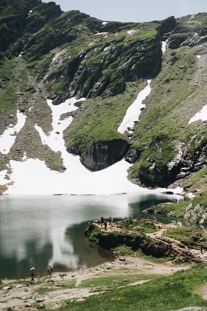 Взгляд ландшафта озера Balea в горах Румынии и Fagaras в лете с снежными пиками