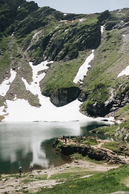 ルーマニアのバレア湖と雪に覆われたピークを持つ夏のフグラシ山の風景を見る