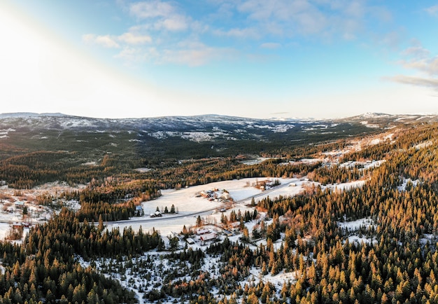 Landscape of a village surrounded by forests covered in the snow under a blue sky and sunlight