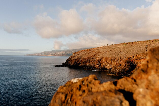 Landscape of wide calm blue ocean with wild orange rocks at sunset Power of nature Freedom Travel