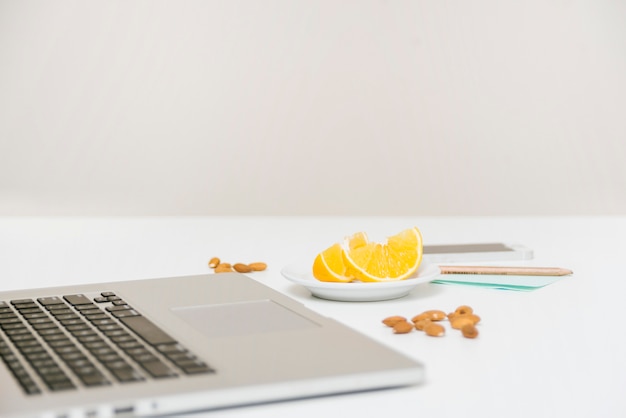 Free photo laptop; almond and sweet lime on white desk