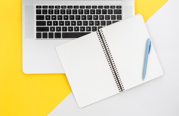 Ноутбук и пустой блокнот на цветном фоне плоской планировки рабочего места