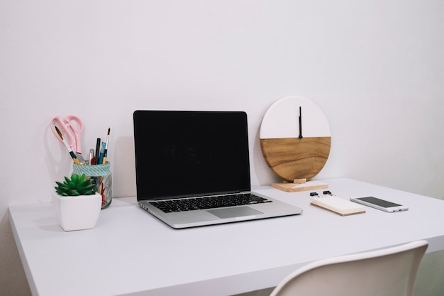 Laptop and clock on white table