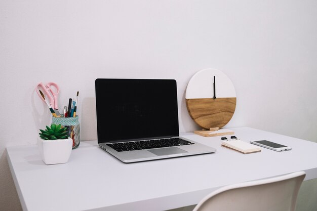 Laptop and clock on white table