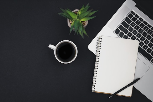 Free photo laptop coffee cup and notepad on black background top view