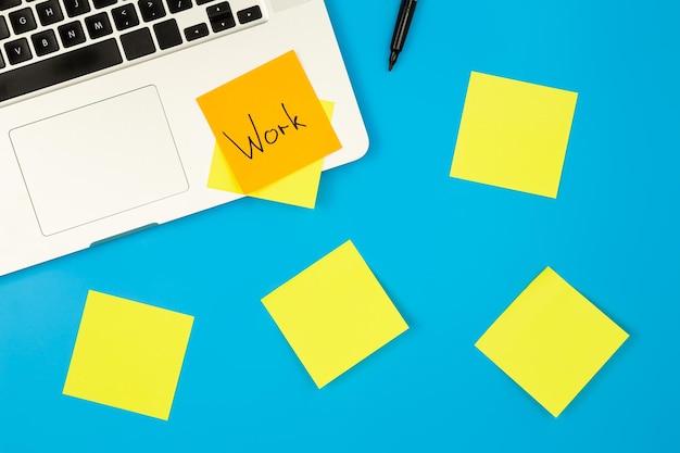 Free photo laptop computer with many sticky notes on a blue background flat lay