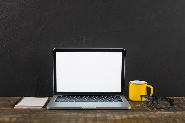 Free photo laptop; cup; notepad and spectacles on wooden surface