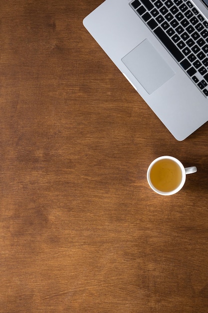 Laptop and cup of tea on a wooden desktop top view