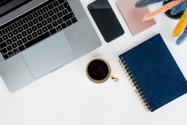 Free photo laptop on a desk with blue notepad