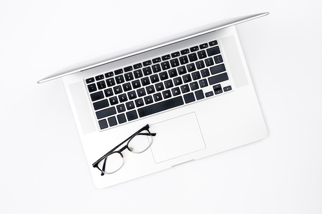 Laptop and glasses on a white background top view