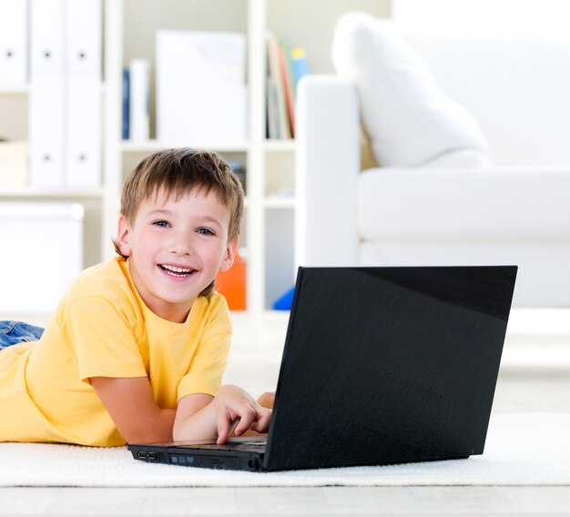 Laptop for happy little boy lying on the floor at home - indoors