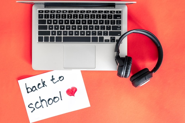 Laptop and headphones on red background back to school concept