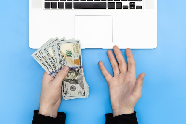 Free photo laptop and money in male hands top view