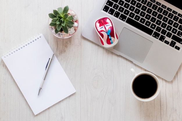 Laptop and mouse near coffee and notebook