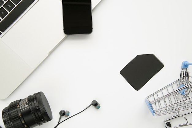 Laptop near smartphone, digital devices and shopping trolley