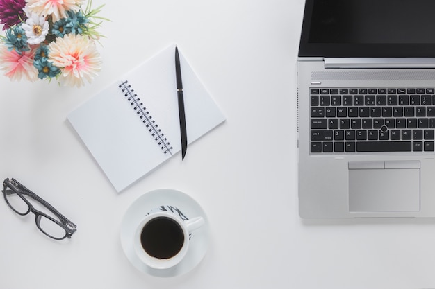 Laptop near stationery and coffee cup