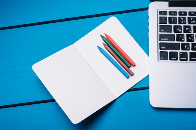 Laptop and notebook on blue desk