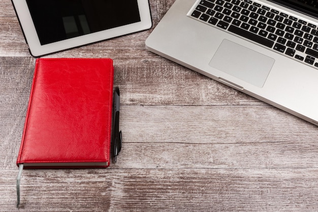 Laptop and a notebook for writing from above view on a wooden background