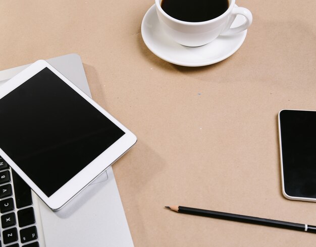 Ноутбук, блокнот, планшет и чашка эспрессо на столе